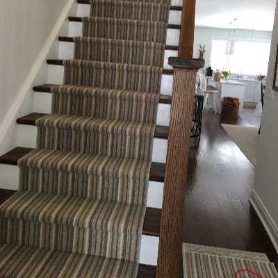 Staircase with striped runner, dark wood steps, and white risers.